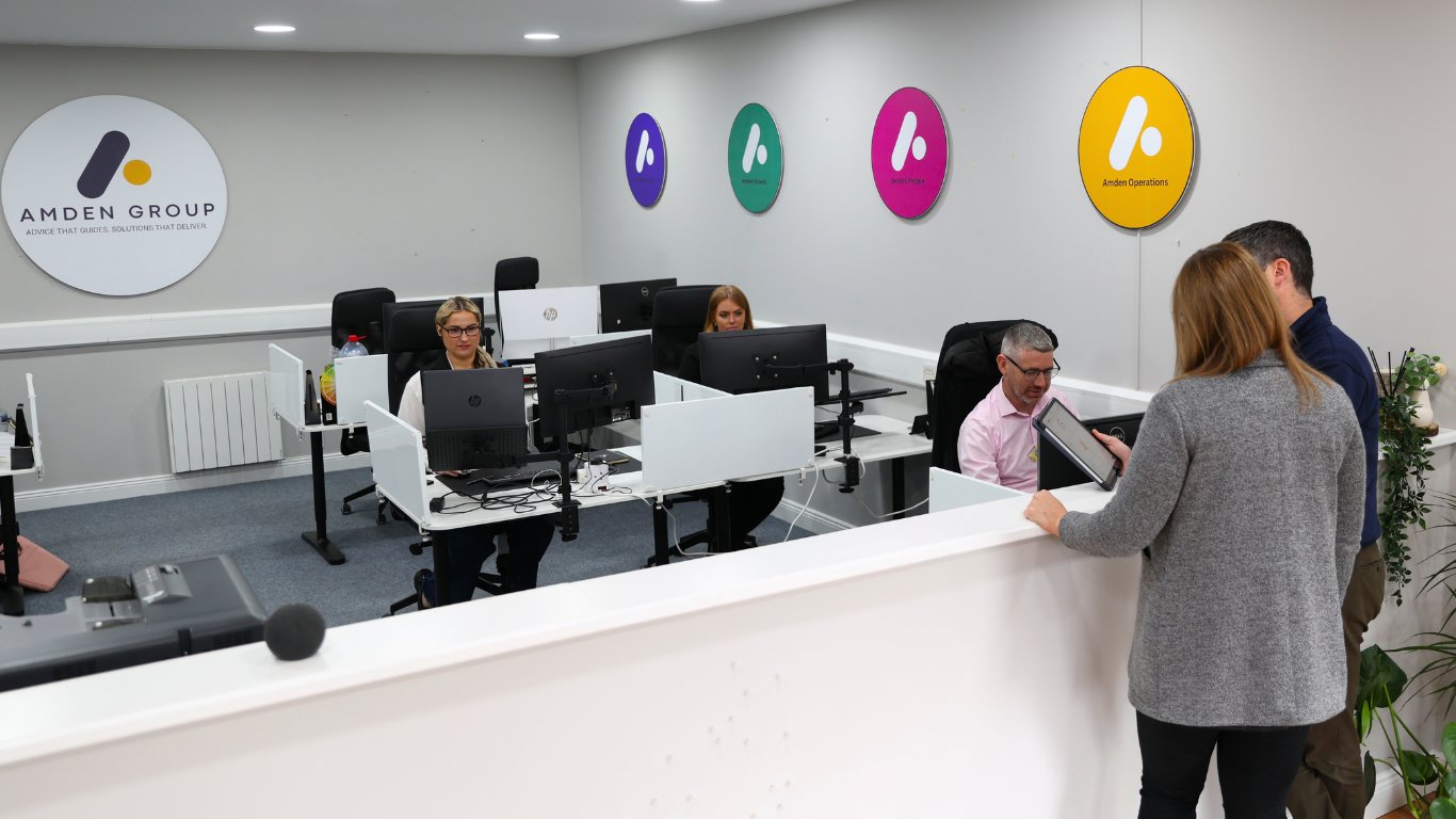 The Amden Group team at work in their office beneath the four brand-division wall discs